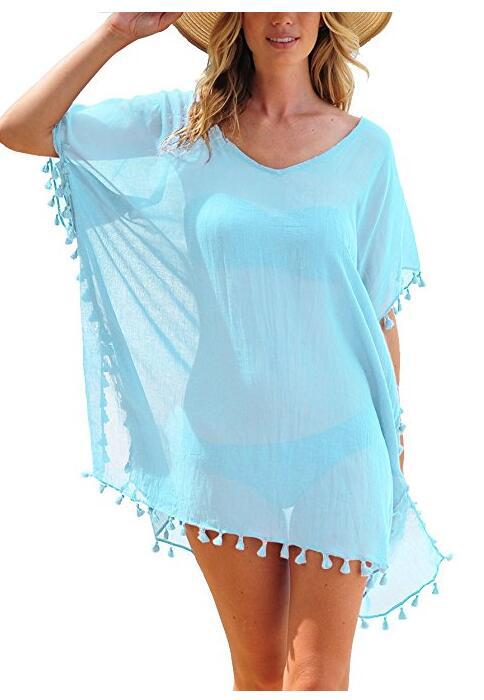 Woman wearing a light blue cover-up with tassels on a white background